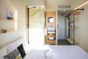 una camera con letto bianco e bagno di Hôtel Life Bordeaux Gare - BG a Bordeaux