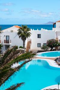 uma piscina com palmeiras em frente a um edifício em Apartamentos Hesperia Bristol Playa em Corralejo