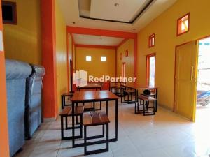 um restaurante com mesas e cadeiras num quarto em Hotel Hing Amimah Mitra RedDoorz em Baubau