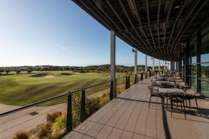 a deck with tables and chairs on a golf course at The Sands Torquay in Torquay