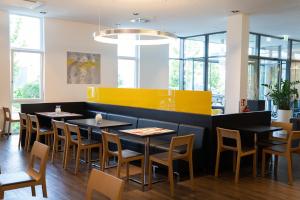 a dining room with tables and chairs and windows at Star G Hotel Premium München Domagkstraße in Munich