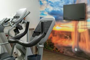 a gym with a flat screen tv and a treadmill at Star G Hotel Premium München Domagkstraße in Munich