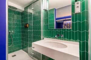 a green tiled bathroom with a sink and a mirror at Room Mate Macarena – Gran Vía in Madrid