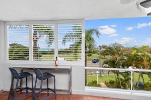 una cocina con 2 sillas y una barra con una gran ventana en Sundeck Gardens, en Maroochydore