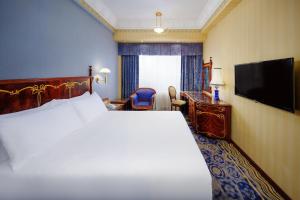 a hotel room with a large bed and a flat screen tv at Hotel Lisboa in Macau