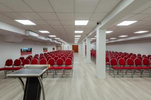 uma sala de conferências vazia com cadeiras e mesas vermelhas em Hotel Barátság em Hajdúszoboszló