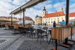 un grupo de mesas y sillas en un patio con un edificio en Apartment Green, en Sibiu