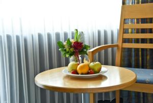 a bowl of fruit and a vase of flowers on a table at Parkhotel "Am Schänzchen" in Andernach