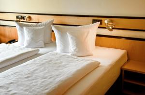 two beds in a hotel room with white sheets and pillows at Parkhotel "Am Schänzchen" in Andernach