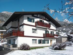 um edifício branco com varandas vermelhas na neve em Apartment Cincelli - Catinaccio by Interhome em Pozza di Fassa