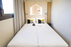 un grande letto bianco in una stanza con finestra di Hôtel Life Bordeaux Gare - BG a Bordeaux