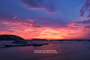 um pôr-do-sol sobre um corpo de água com barcos em Ari La Casa em Nusa Penida