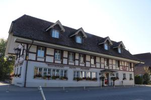 un grand bâtiment blanc avec un toit noir dans l'établissement Hotel & Restaurant Sternen Köniz bei Bern, à Berne