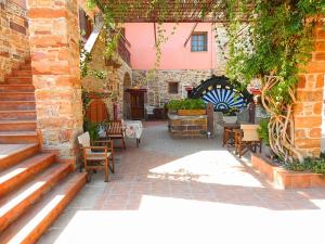 un patio avec des chaises et des tables ainsi qu'un bâtiment dans l'établissement Mouzaliko Guesthouse Mansion, à Kambos