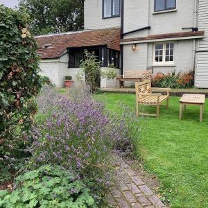 een tuin met een bank en paarse bloemen in een tuin bij The Jolly Sportsman in Lewes