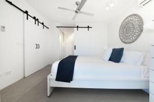 a white bedroom with a white bed and a ceiling fan at Centrepoint Apartments Caloundra in Caloundra