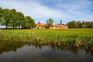 una casa grande en un campo junto a un cuerpo de agua en Hotel Gut Immenhof, en Malente