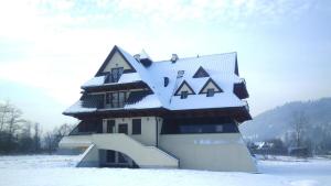 un edificio con techo cubierto de nieve en la nieve en Willa Pawlikowskich, en Poronin