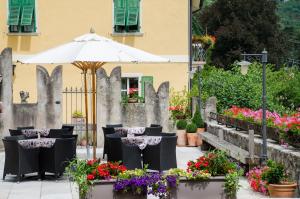 een patio met tafels en bloemen en een parasol bij Garnì San Giorgio Della Scala Rooms and Breakfast in Trento