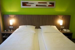 two beds in a room with green walls and two lamps at Hotel Ambiente Walldorf in Walldorf