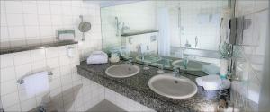 a bathroom with two sinks and a large mirror at Hotel Ambiente Walldorf in Walldorf