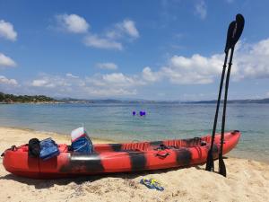 - un kayak rouge assis sur la plage avec un rame dans l'établissement Harisis Apartments, à Olympiakí Aktí