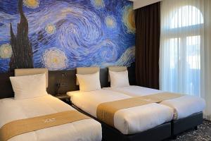 2 Betten in einem Zimmer mit Wandgemälde in der Unterkunft Hotel Van Gogh in Amsterdam