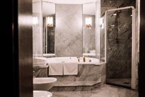 a bathroom with a tub and a shower and a sink at Rahat Palace Hotel in Almaty