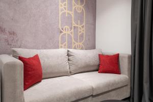 a couch with two red pillows in a living room at SAVOY residence in Osijek