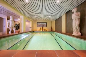 ein Pool in einem Hotel mit Statuen an der Wand in der Unterkunft Seilers Vintage Hotel & Spa in Kandersteg