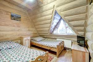 a bedroom with two beds in a log cabin at Pokoje Pod Lasem in Kościelisko