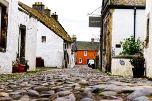 een geplaveide straat in een dorp met gebouwen bij Stunning & unique apt in Culross in Culross