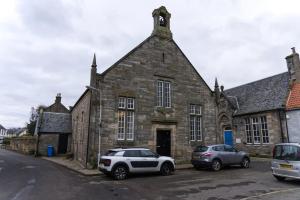 twee auto's geparkeerd voor een stenen gebouw bij Stunning & unique apt in Culross in Culross