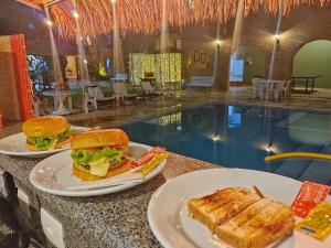 dos platos de comida en una mesa junto a una piscina en Giprita Wellness Hotel Ubatuba, en Ubatuba