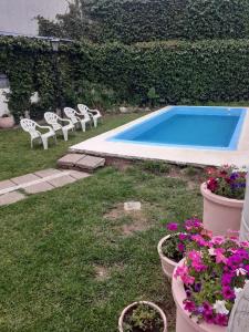 a pool with chairs and flowers in a yard at Hotel Mediterraneo in Villa Carlos Paz