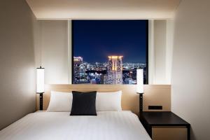 um quarto com uma janela com vista para a cidade em Hotel Hankyu RESPIRE OSAKA em Osaka