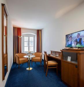 une chambre d'hôtel avec une table, des chaises et une télévision dans l'établissement Altstadthotel der Patrizier, à Ratisbonne