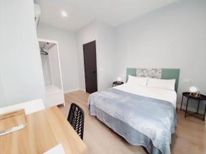 Schlafzimmer mit einem weißen Bett und einem Holztisch in der Unterkunft Apartamentos Vega by gaiarooms in Salamanca