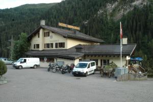 un bâtiment avec des voitures et des motos garées devant lui dans l'établissement Hotel Restaurant Walserhof, à Medels im Rheinwald