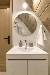 bagno con lavandino bianco e specchio di Hill House Apartamenty a Białka