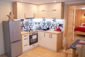 a kitchen with white cabinets and a refrigerator at Apartament Jagodzianka Biały Dunajec in Biały Dunajec