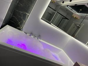 ein Badezimmer mit einer mit lila Wasser gefüllten Badewanne in der Unterkunft Apartament Primavera 2 z Sauną i Jacuzzi in Kielce