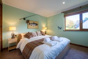 1 dormitorio con 1 cama grande y toallas. en Tanglewood Lodge, en Lossiemouth