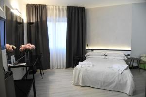 una camera da letto con letto, lenzuola e cuscini bianchi di Brianteo Hotel and Restaurant a Burago di Molgora