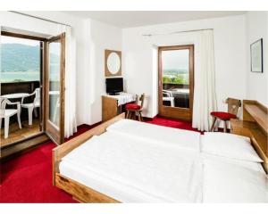 a bedroom with a large white bed and a desk at Pension Hasslhof in Caldaro