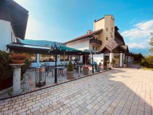 un patio avec des tables et des chaises en face d'un bâtiment dans l'établissement Smy Koflerhof Wellness & Spa Dolomiti, à Rasun di Sopra