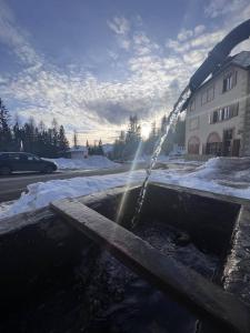 um banco de madeira com uma fonte de água na neve em Hotel Al Sasso di Stria em Andraz