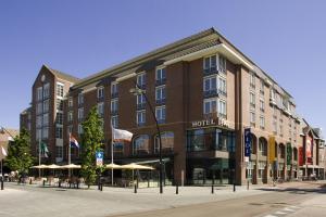 um edifício de hotel numa rua da cidade com guarda-sóis em Hotel Theater Figi em Zeist