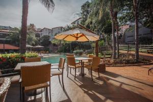 - une table et des chaises avec un parasol à côté de la piscine dans l'établissement Rio Quente Resorts - Hotel Luupi, à Rio Quente