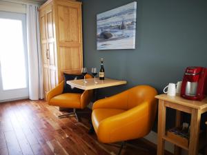 una sala da pranzo con tavolo e sedie arancioni di Au Cachalot Caché le gîte hôtel a Tadoussac